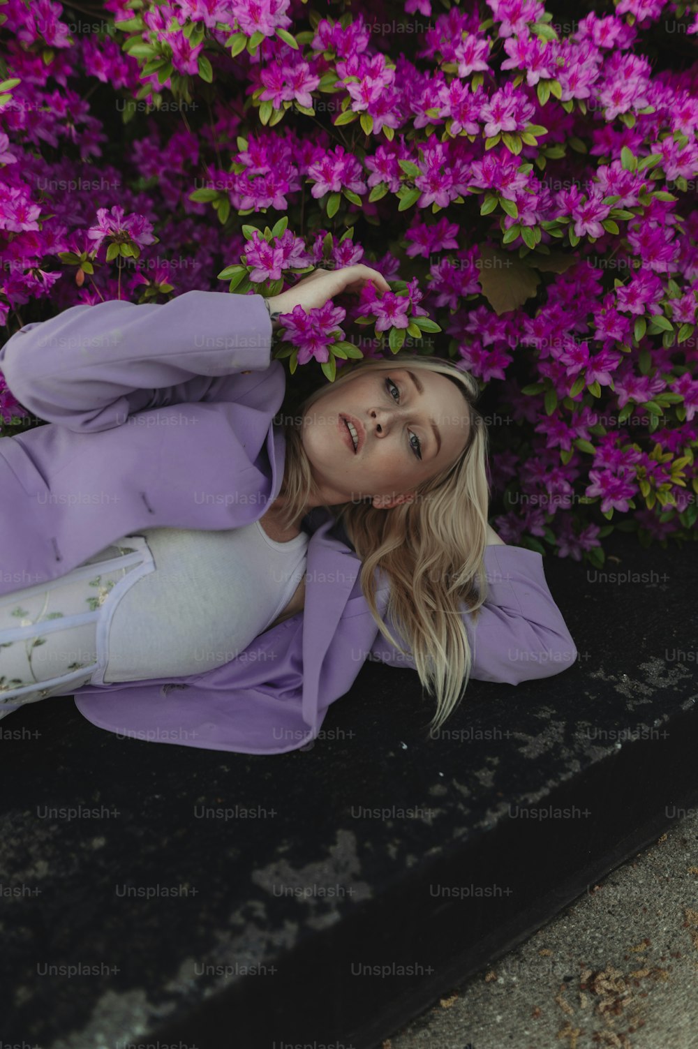 a woman laying on the ground in front of purple flowers