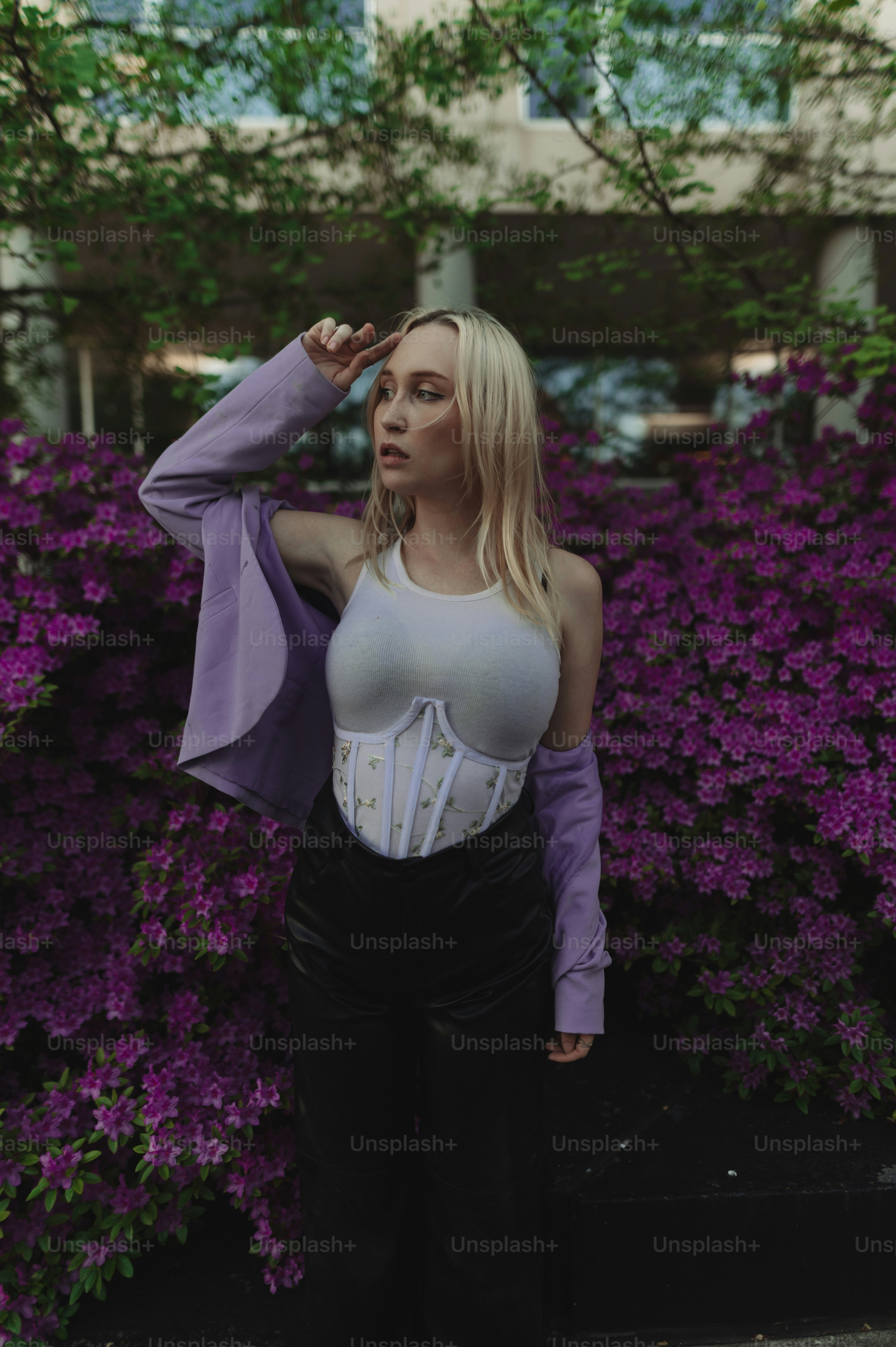 a woman standing in front of purple flowers