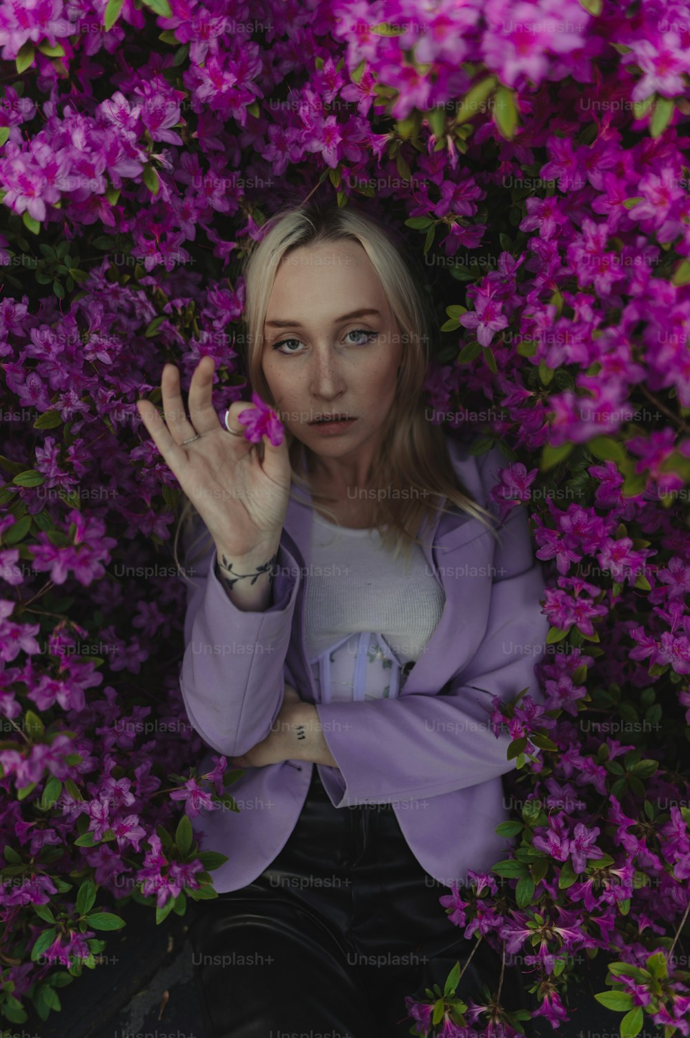 Una mujer sentada en un arbusto de flores púrpuras