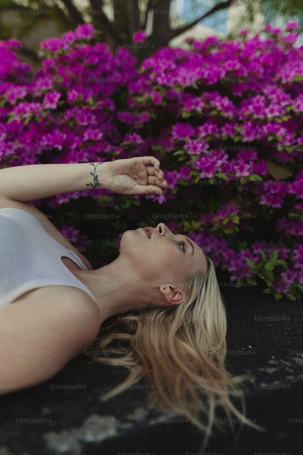 Una donna sdraiata a terra davanti a fiori viola