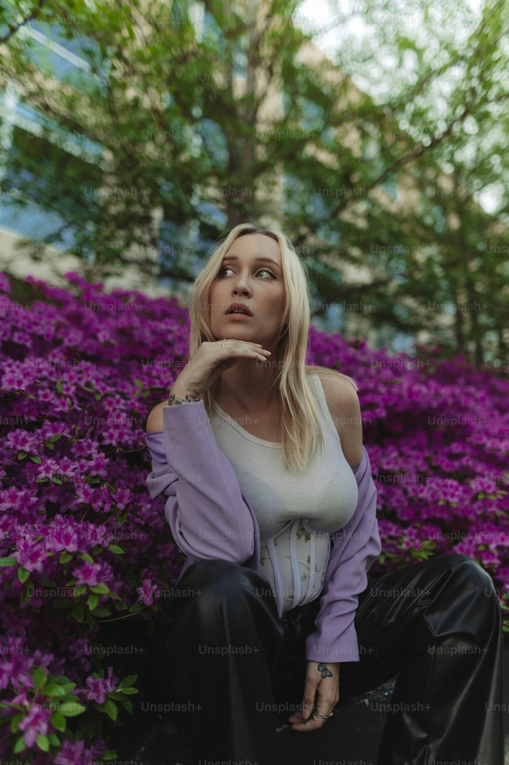 a woman sitting on a bench in front of purple flowers