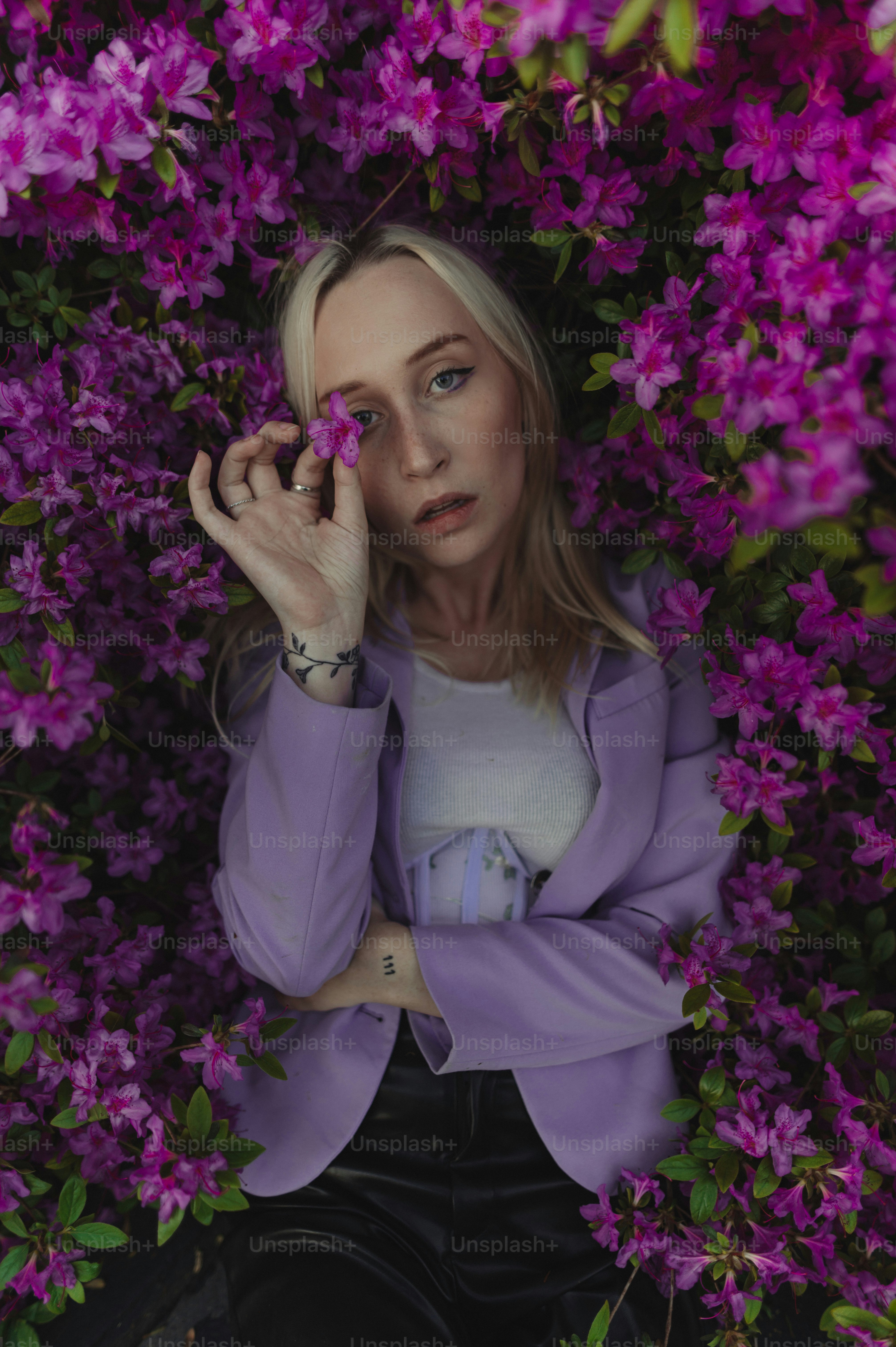 Eine Frau in einer lila Jacke ist von lila Blumen umgeben