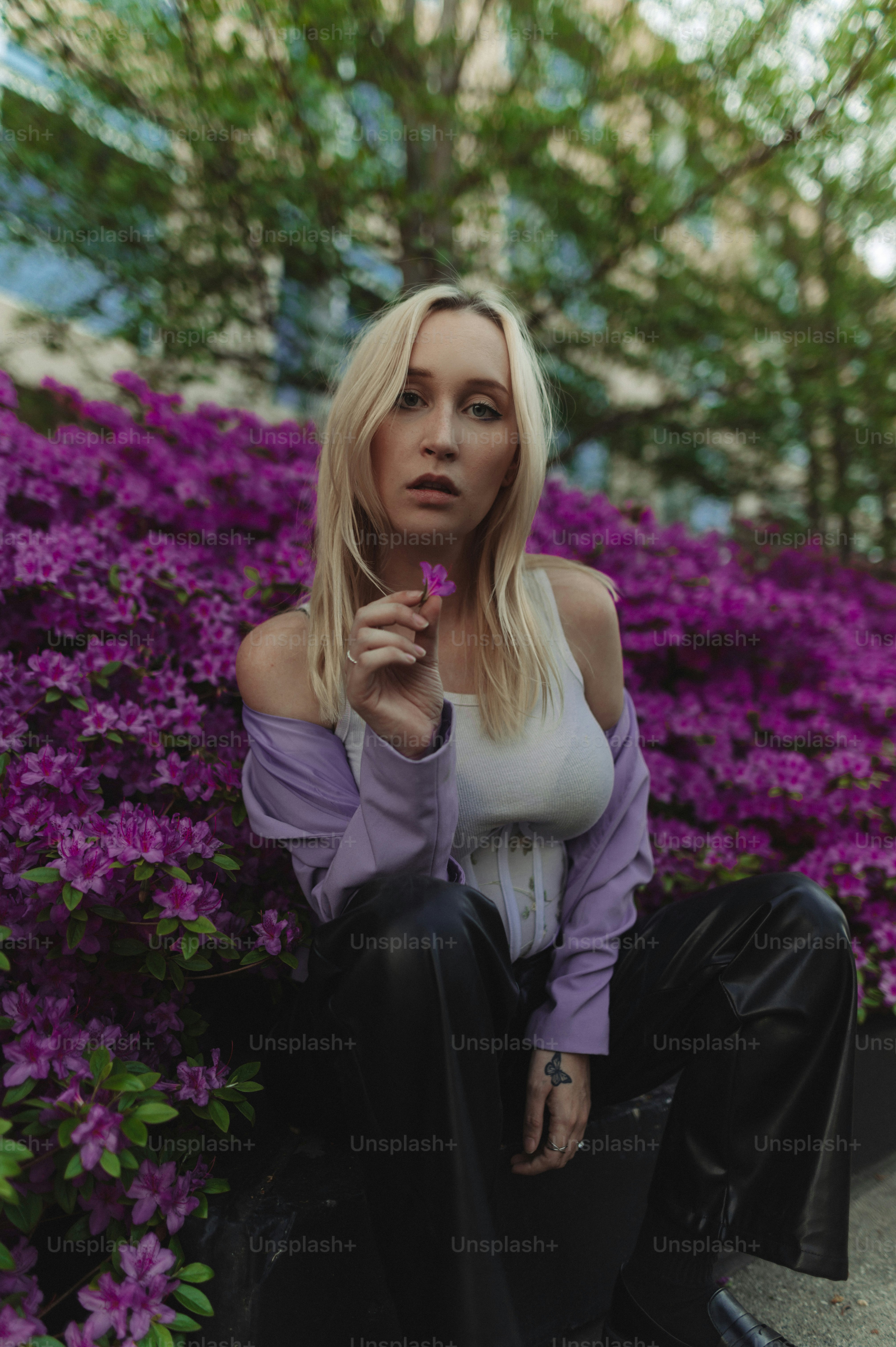 Eine Frau, die auf einer Bank vor lila Blumen sitzt