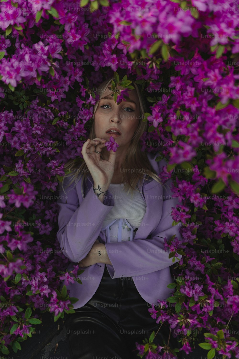 Eine Frau in einer lila Jacke ist von lila Blumen umgeben