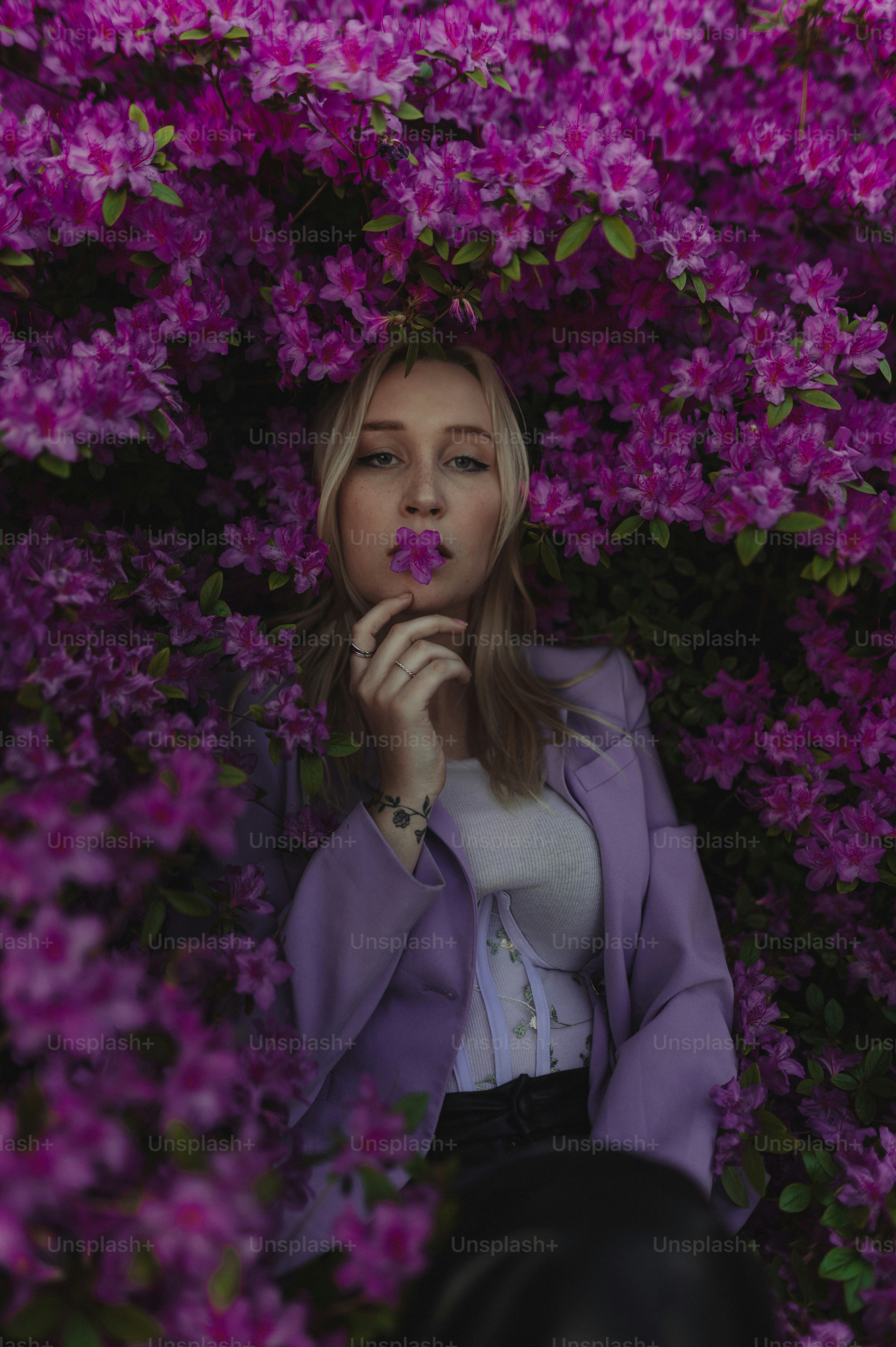 Eine Frau sitzt in einem Busch aus lila Blumen