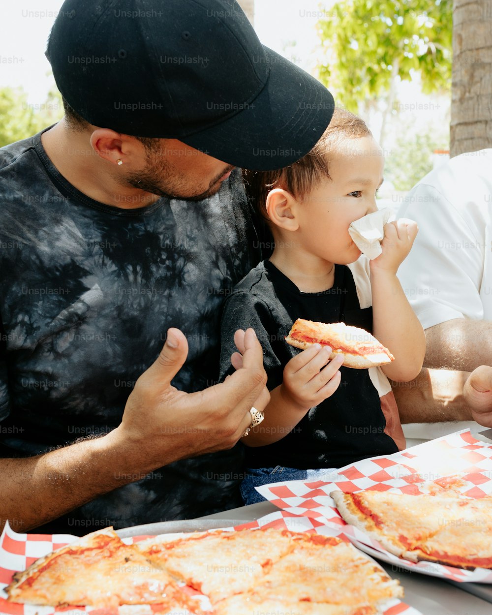 a man and a child eating pizza at a table