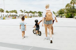 a woman walking with two children on a sidewalk