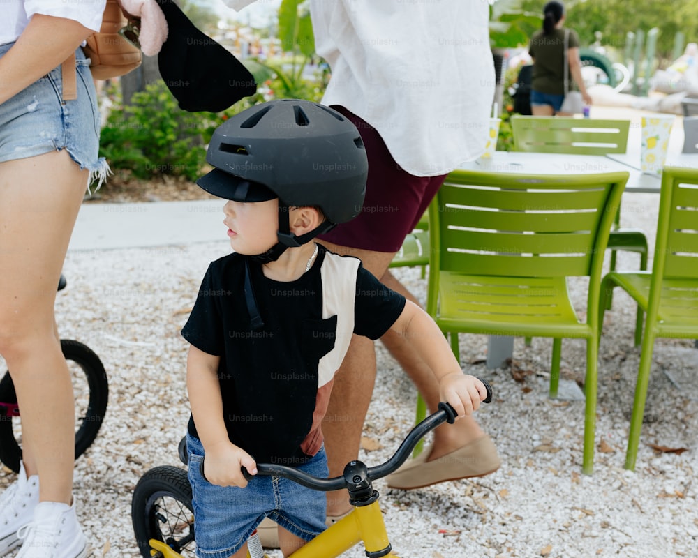 a young boy riding a tricycle with a helmet on