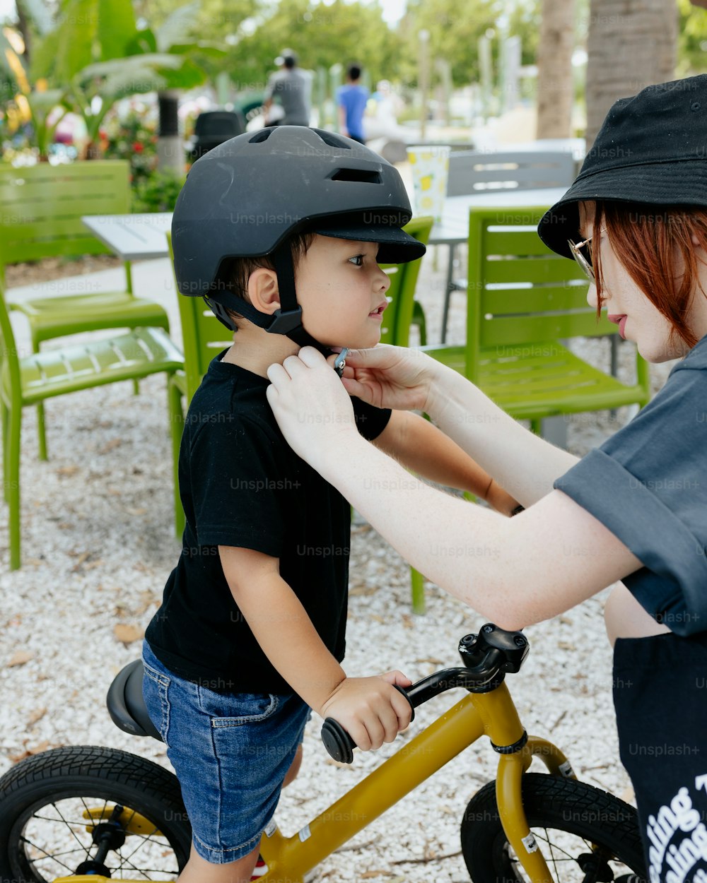 a woman helping a young boy put on a helmet