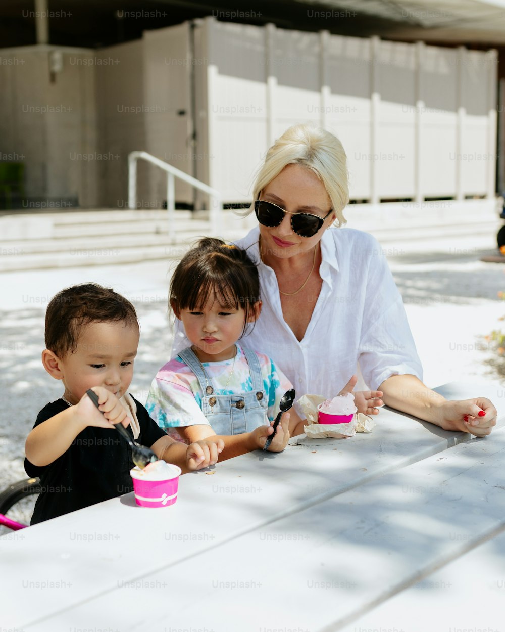 a woman and two children sitting at a picnic table