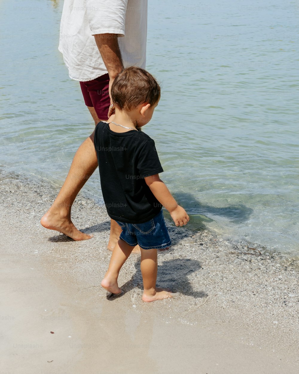 a man and a little boy walking on the beach