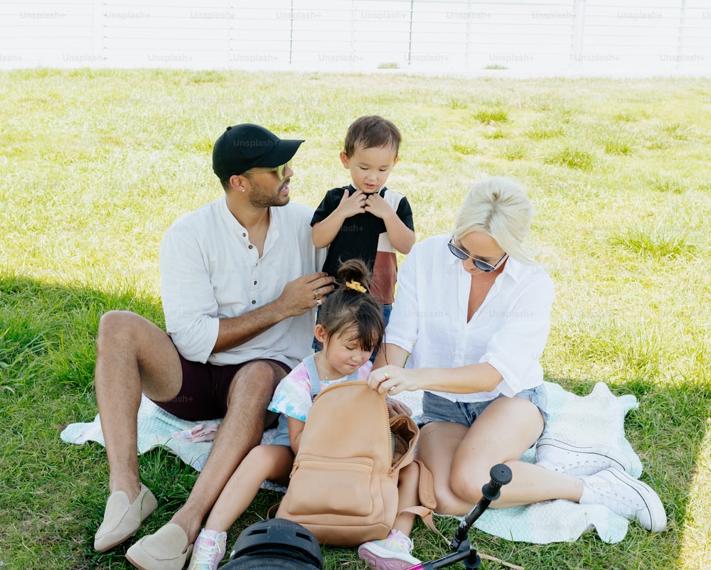 a man, woman, and child sitting on a blanket in the grass