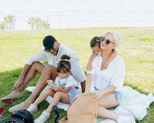 a family sitting on a blanket in the grass