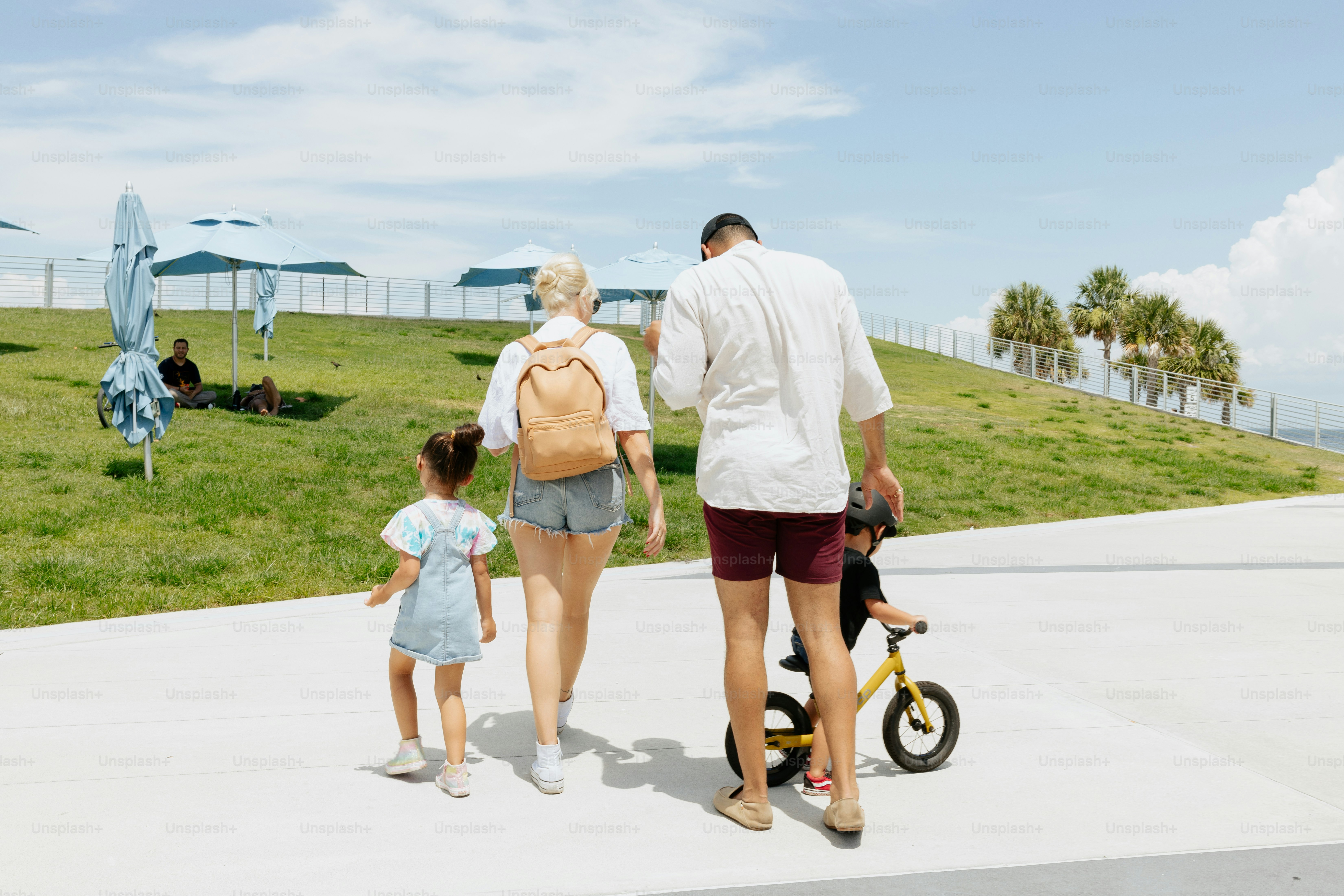 Un hombre y una mujer caminando con un niño en un scooter
