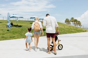 a man and a woman walking with a child on a scooter
