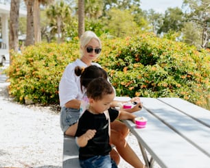 a woman sitting next to a little girl on a bench