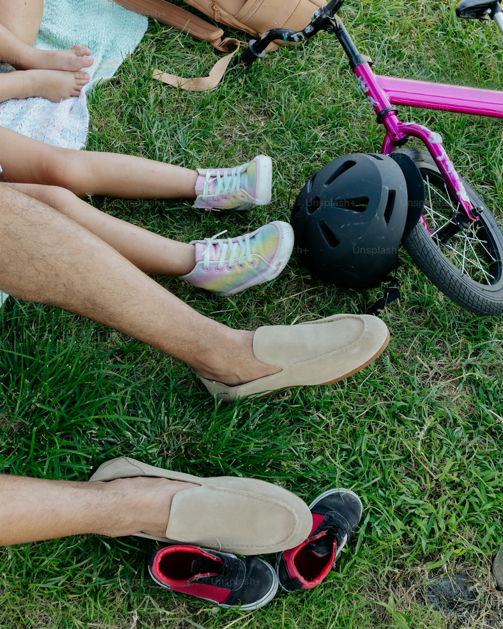 Un uomo e una bambina seduti sull'erba accanto a una bici rosa