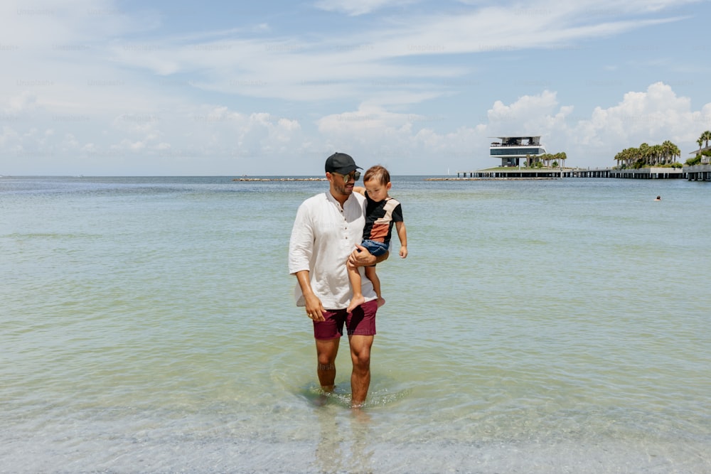 a man holding a little girl while standing in the ocean