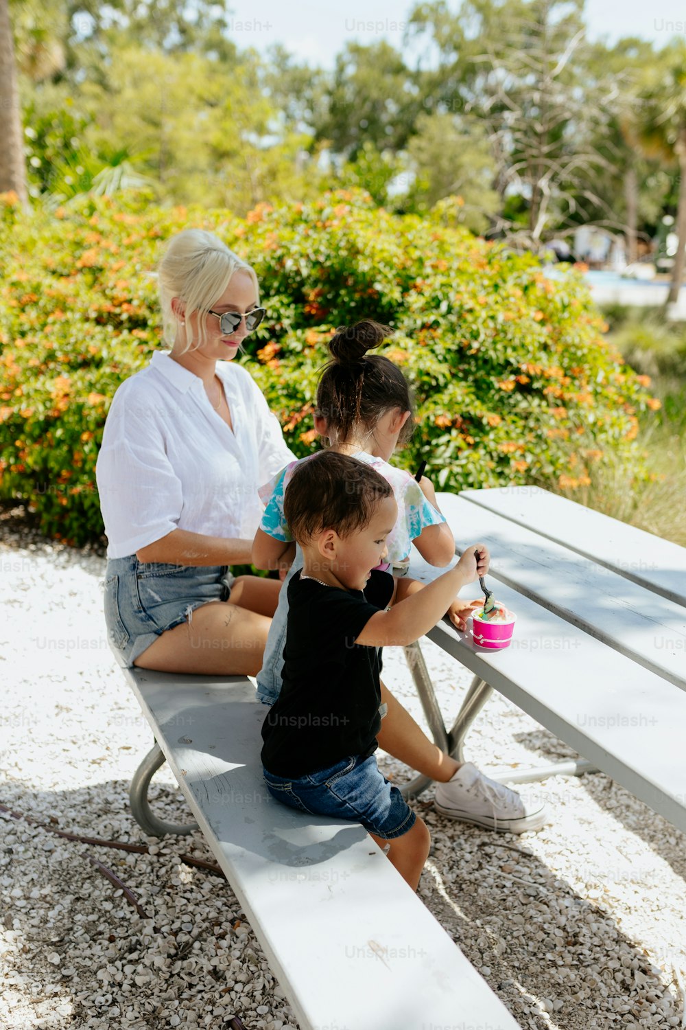 a woman and two children sitting at a picnic table