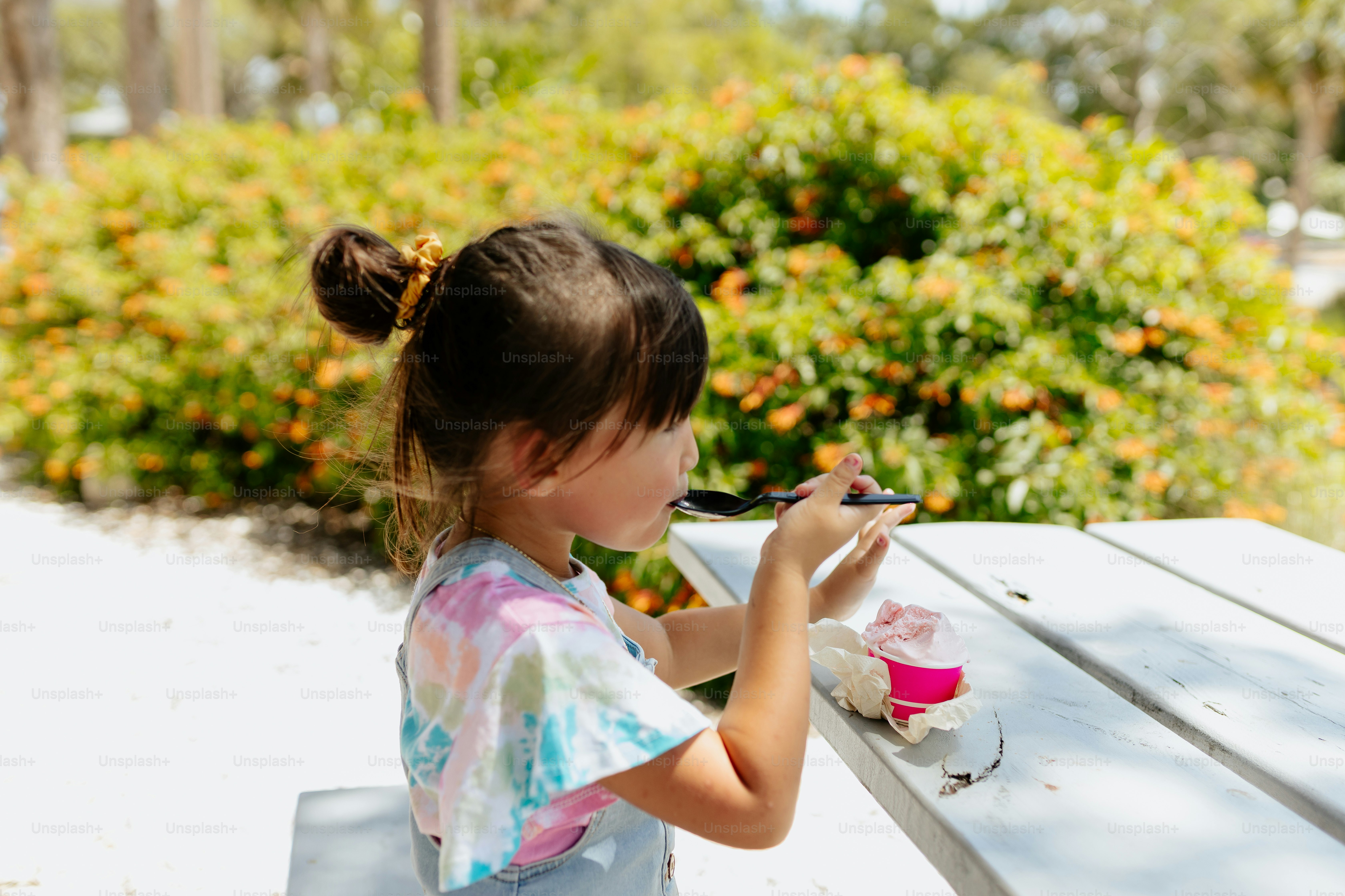 a little girl sitting at a table eating food