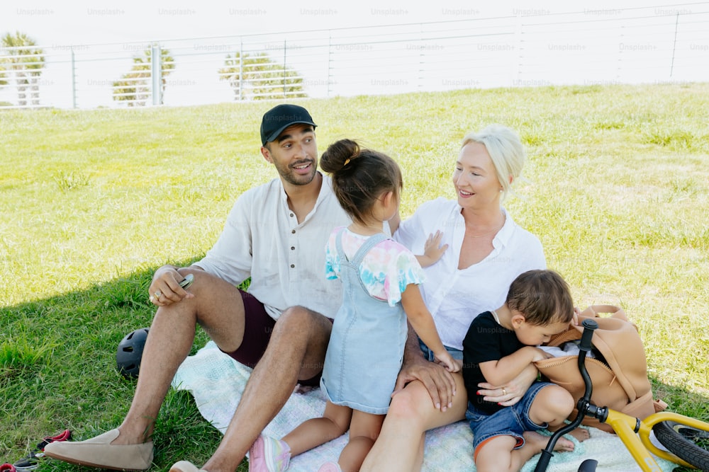 a family sitting on a blanket in the grass