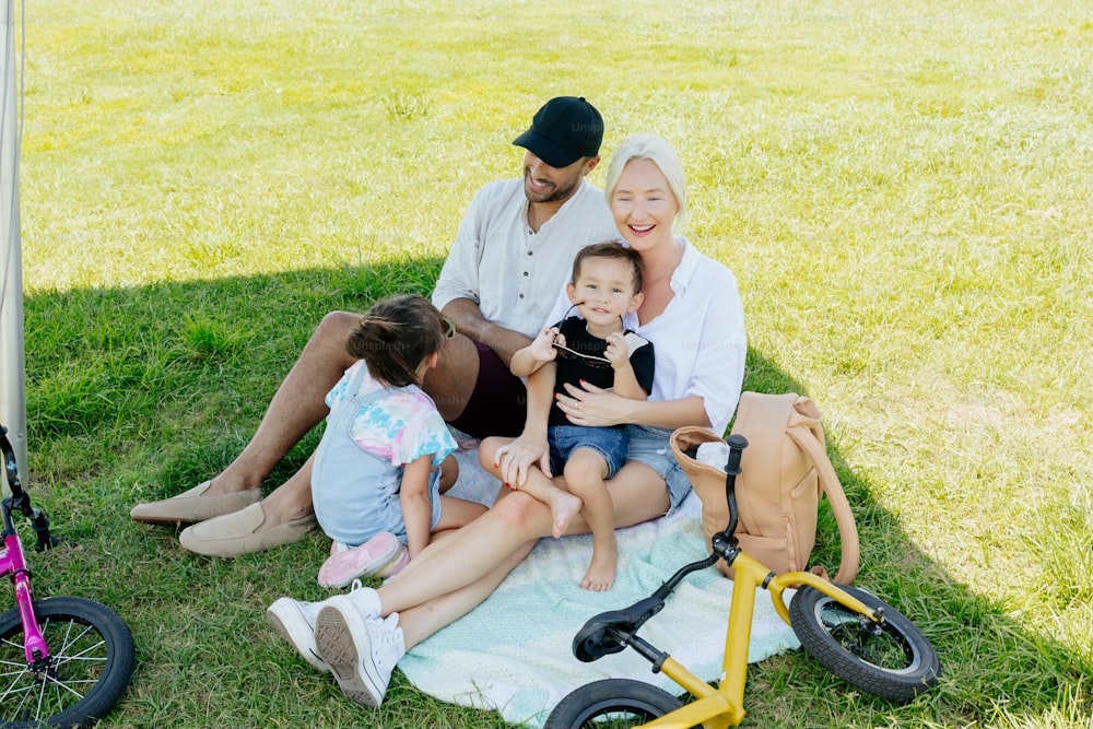 Une famille assise sur une couverture dans l’herbe