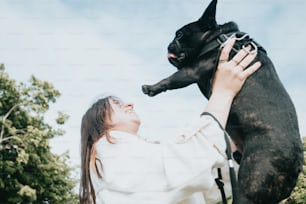 a woman holding a black dog up to her face
