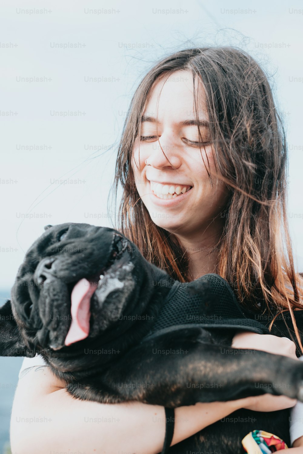Una mujer sosteniendo un perro negro en sus brazos