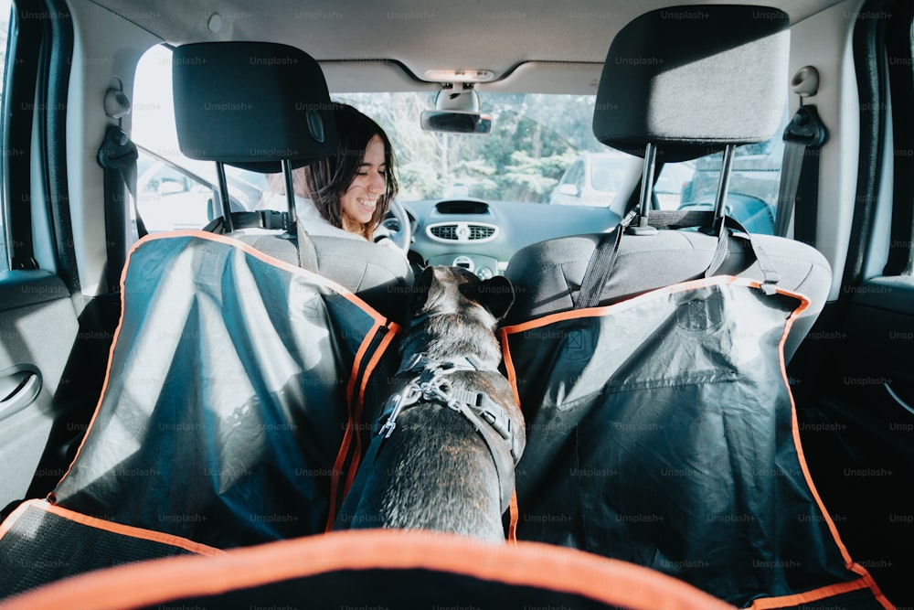 a woman sitting in the back seat of a car with a dog