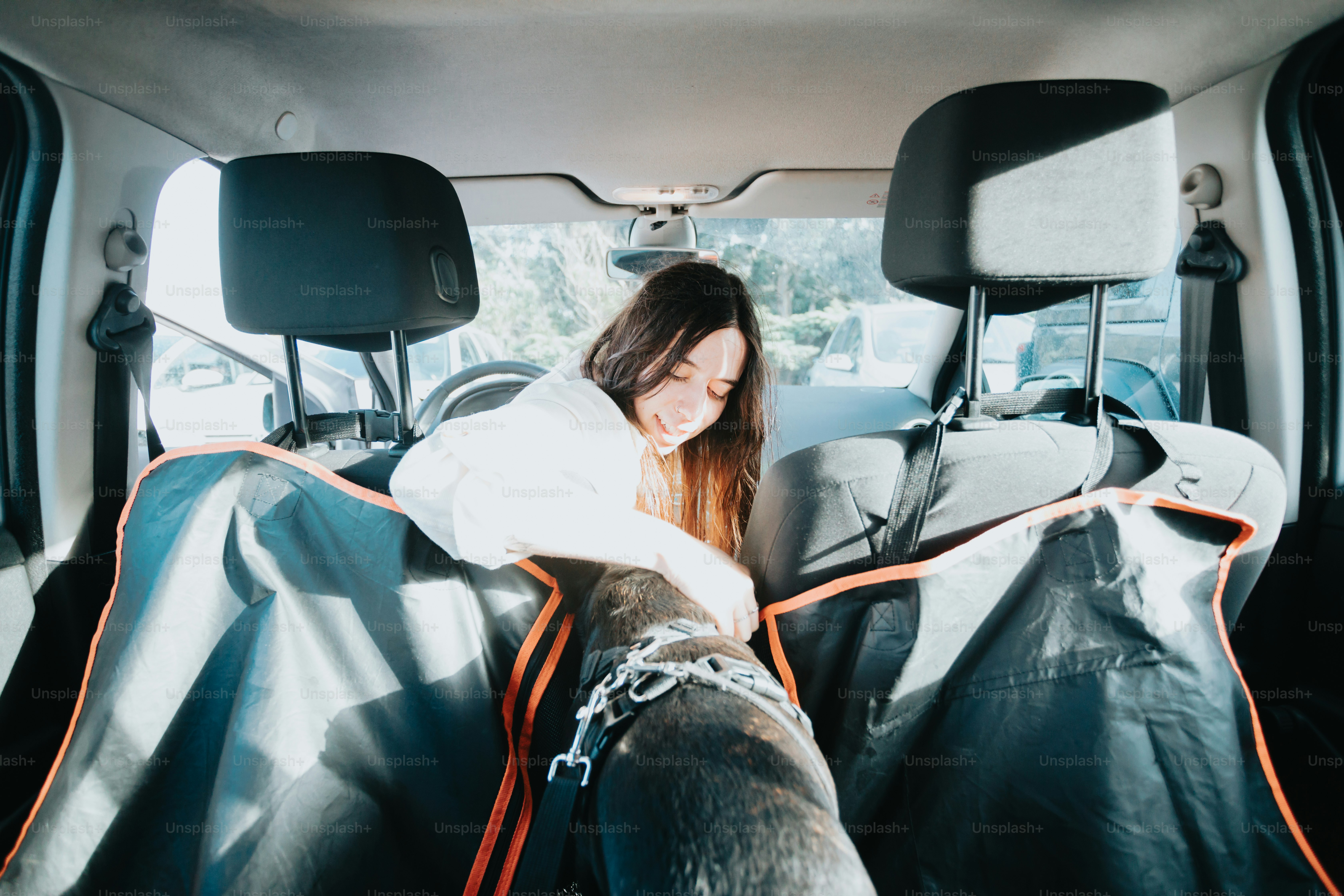 a woman sitting in the back of a car with her dog