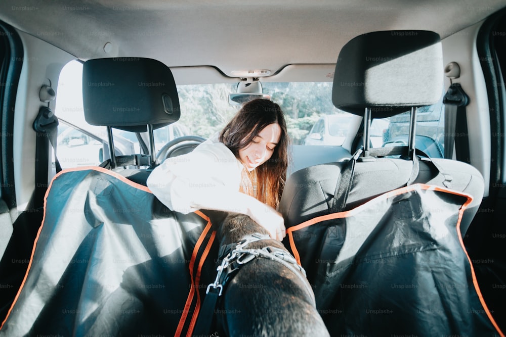 a woman sitting in the back of a car with her dog