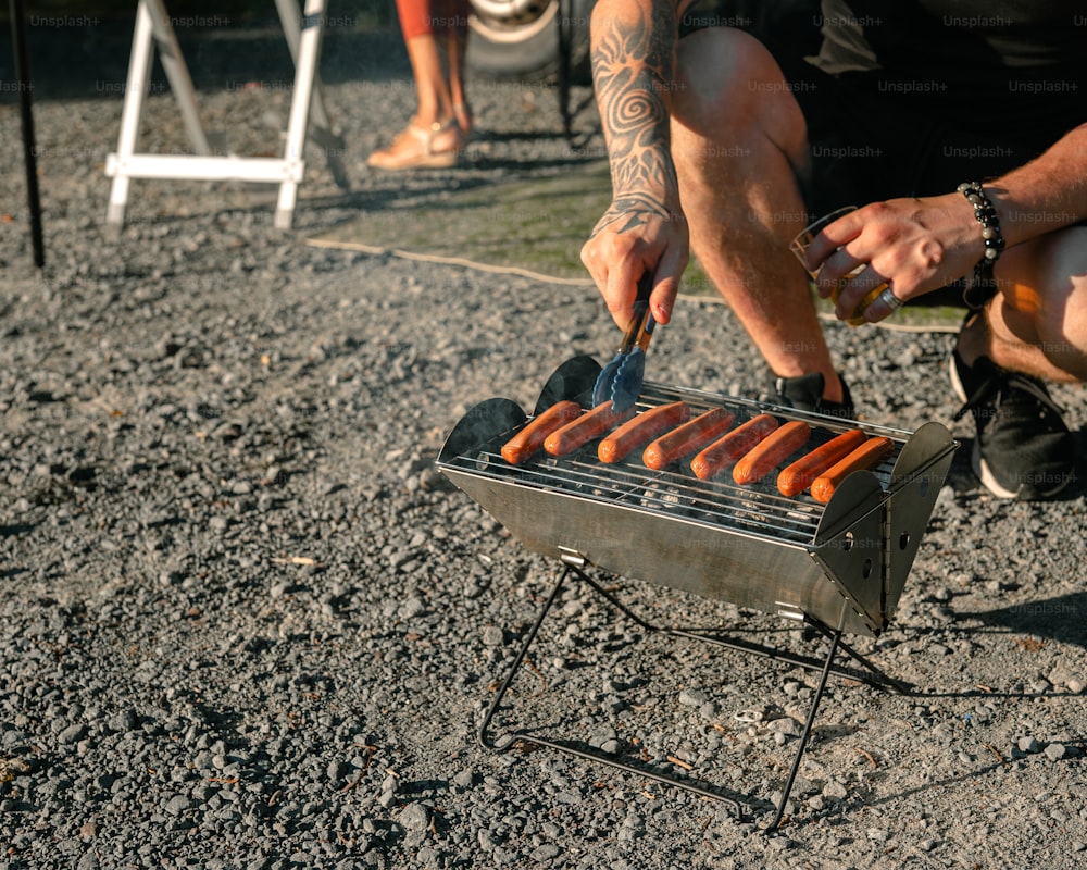 a man is cooking hot dogs on a grill