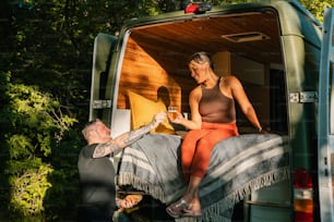 a woman sitting on the back of a green van