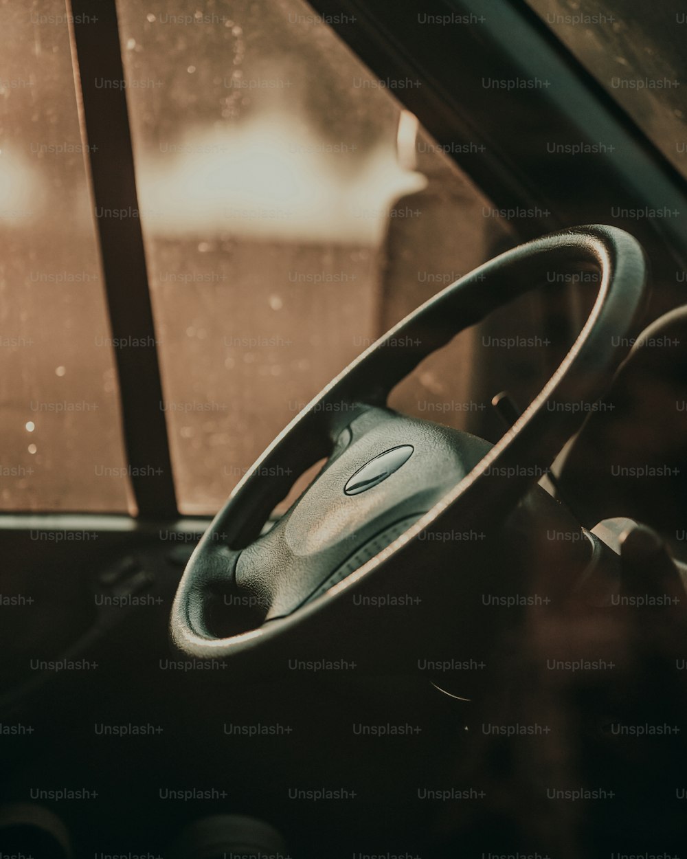 a steering wheel of a car with rain drops on the windshield