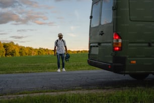 a man standing next to a green bus on a road