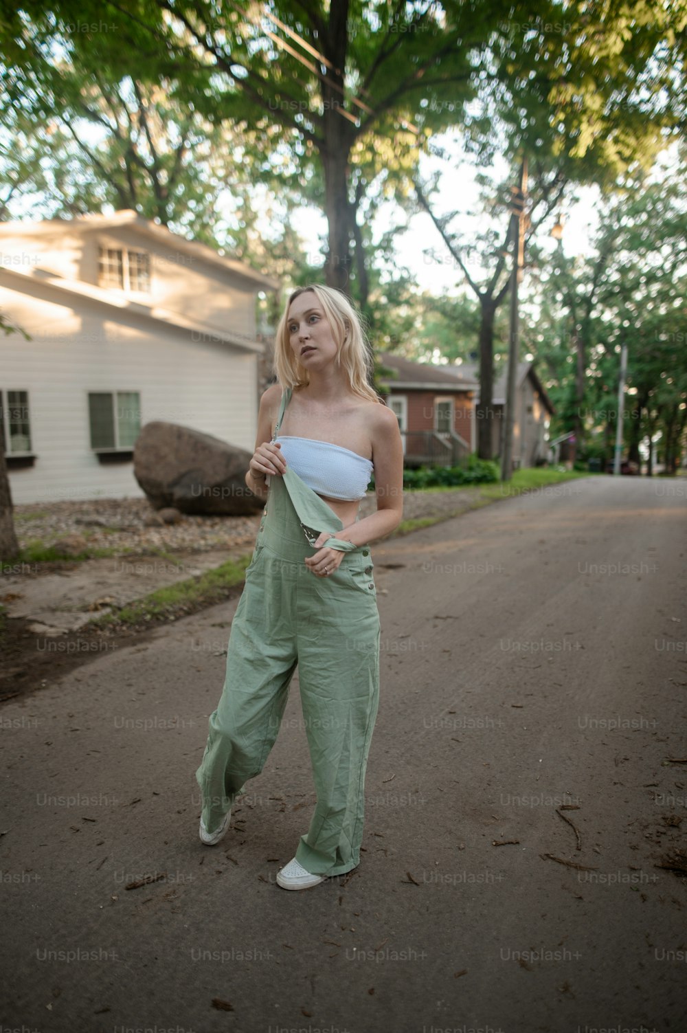 a woman in a white top and green pants