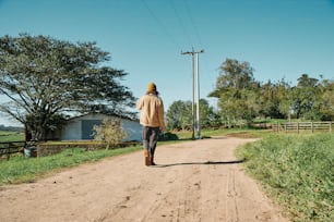 a man walking down a dirt road in the country