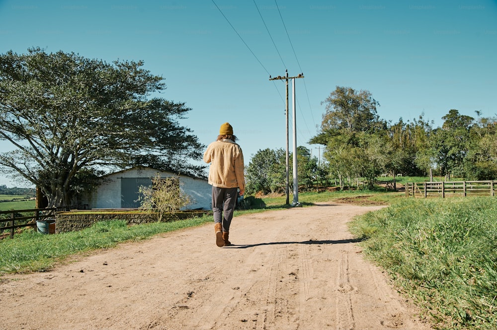 a man walking down a dirt road in the country