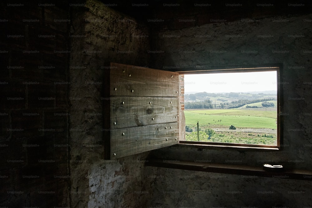 a window in a stone building with a view of a field