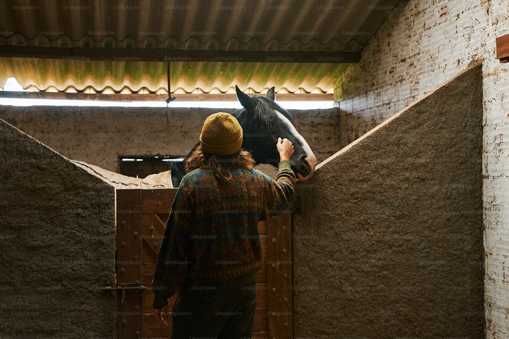 a man standing next to a horse in a stable