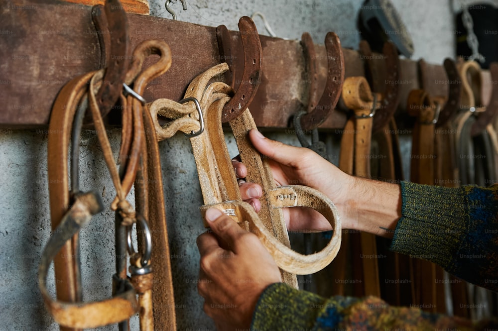 a person holding a pair of scissors in front of a wall of horse tacks