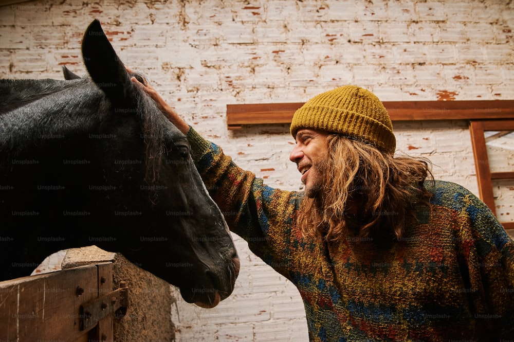 a man petting a horse next to a brick wall