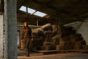 a woman standing in front of a pile of hay