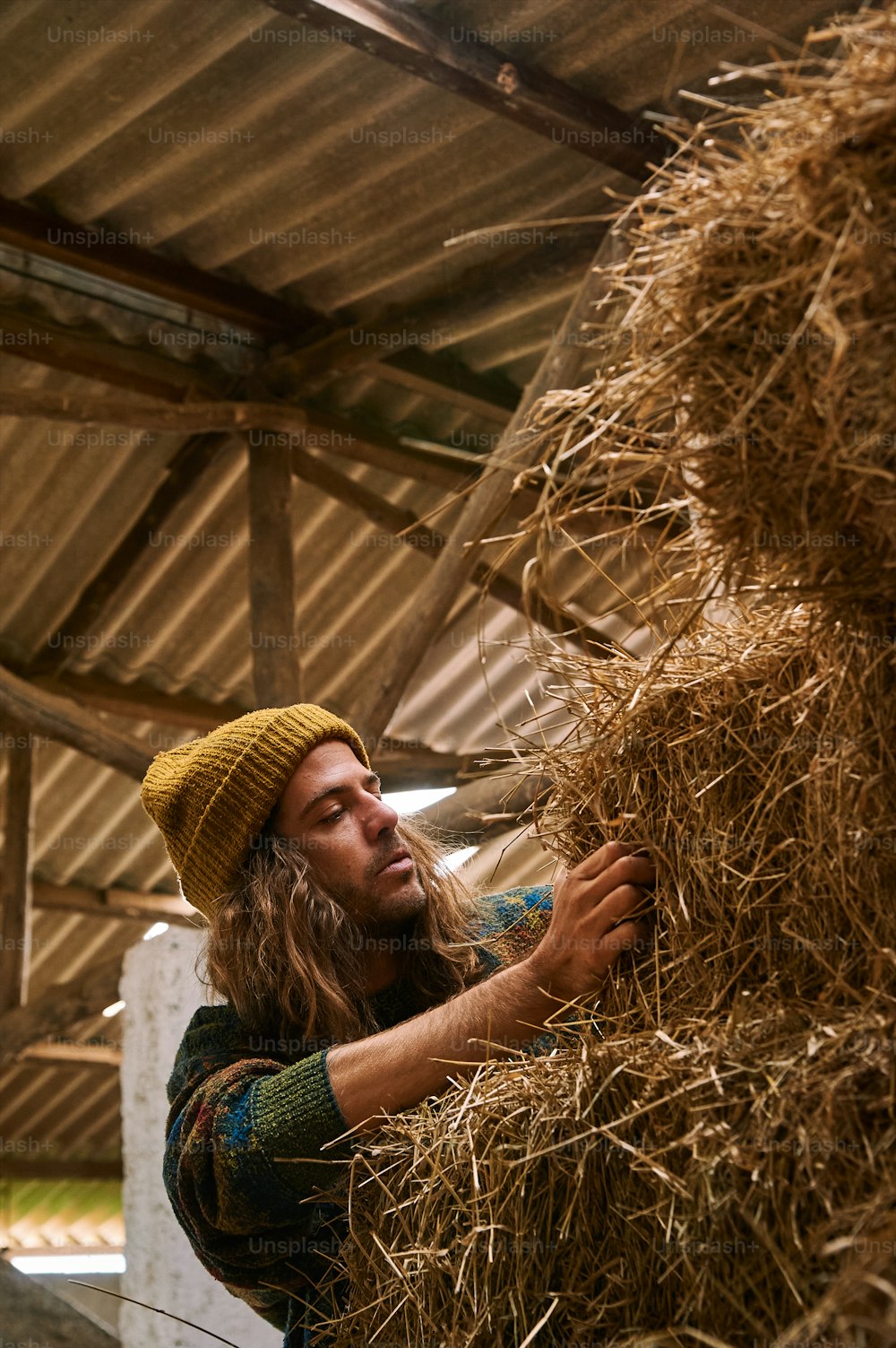 a man in a straw hat is holding a bale of hay