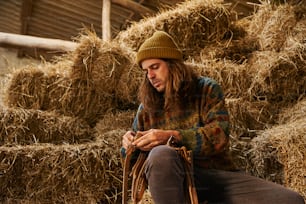 a man sitting on a pile of hay looking at his cell phone
