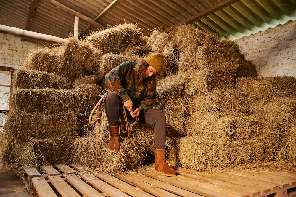 a woman sitting on top of a pile of hay