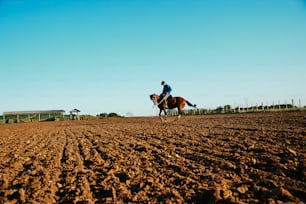 a man riding a horse across a dirt field