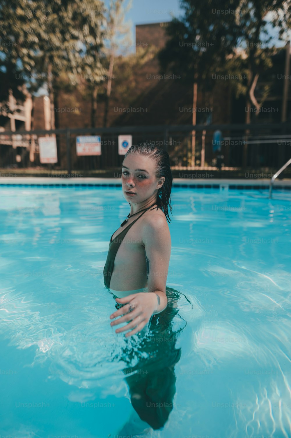 Una mujer en bikini parada en una piscina