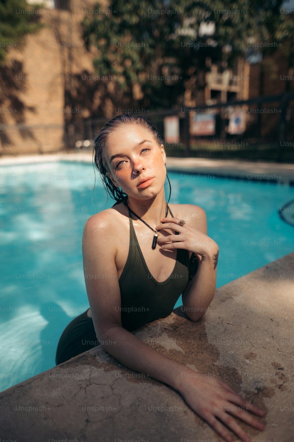 uma mulher em traje de banho sentada ao lado de uma piscina