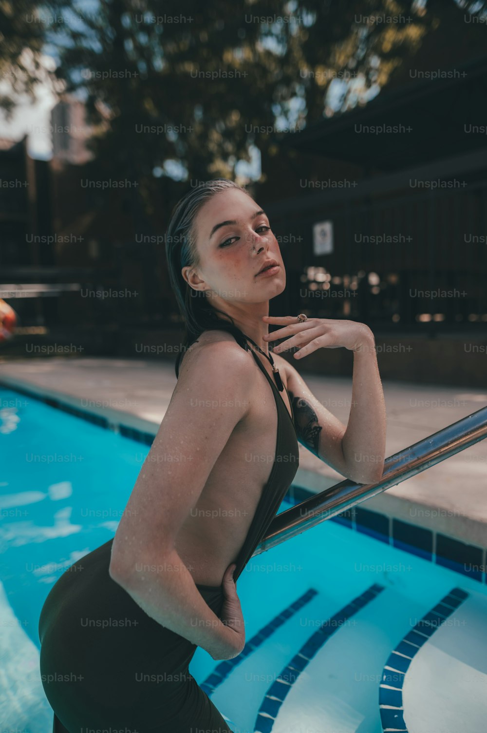 uma mulher encostada a um corrimão ao lado de uma piscina